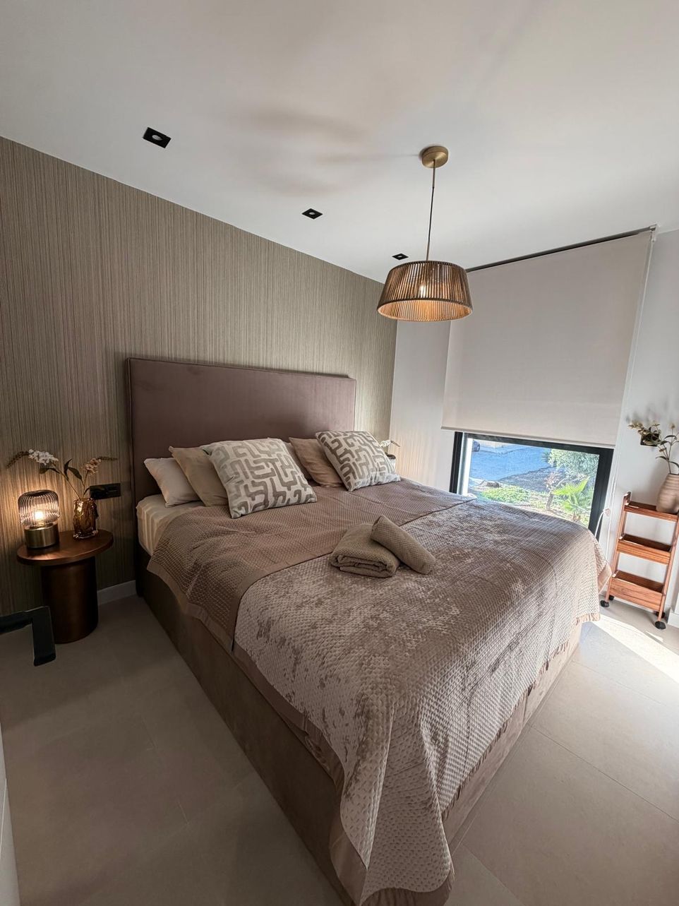 Slaapkamer met tweepersoonsbed, fluwelen hoofdbord en rieten hanglamp